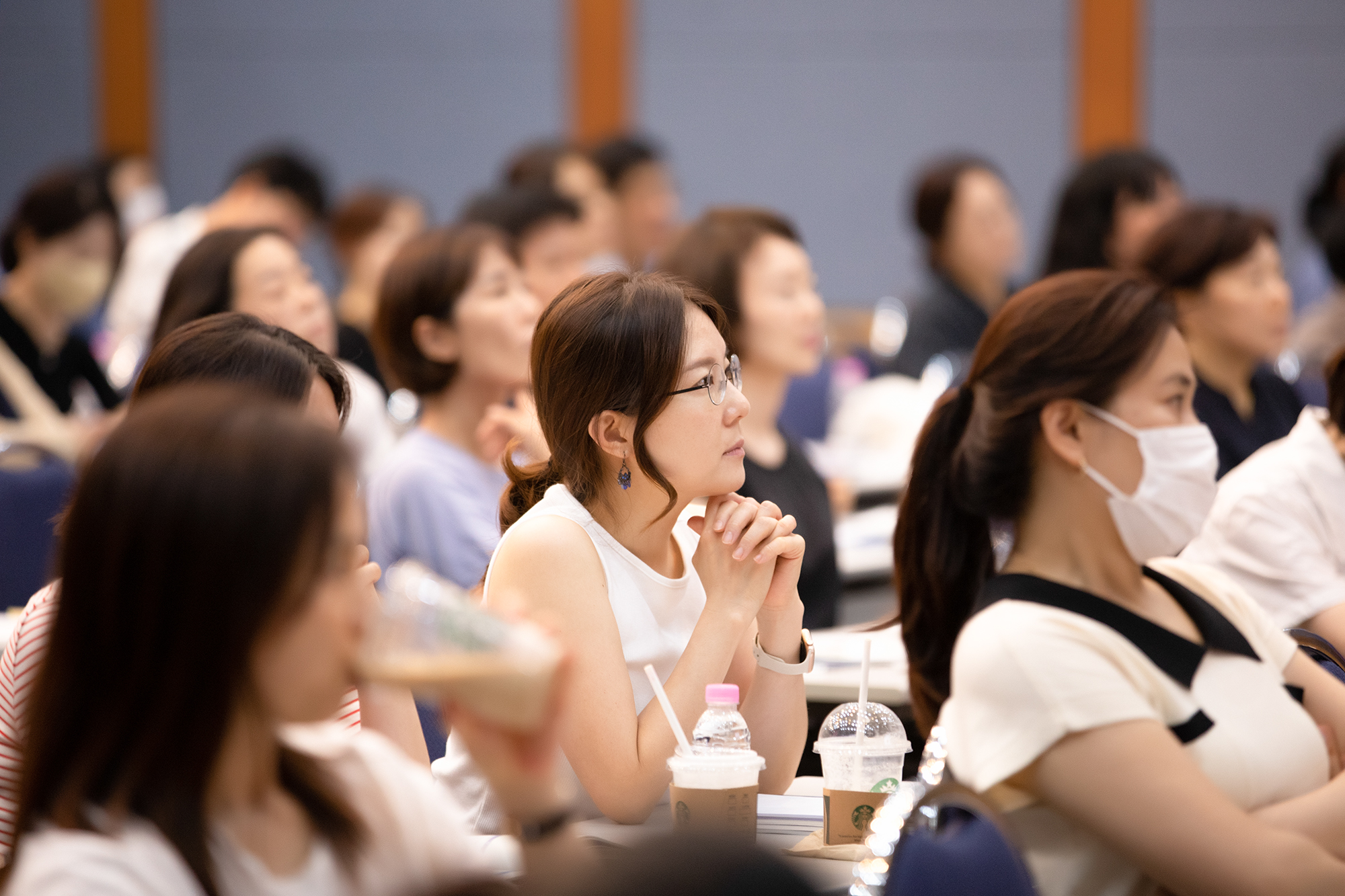 앞을 보며 집중하는 학부모들의 사진. 가운데 있는 한 명을 제외하고 나머지는 흐릿하게 보인다.